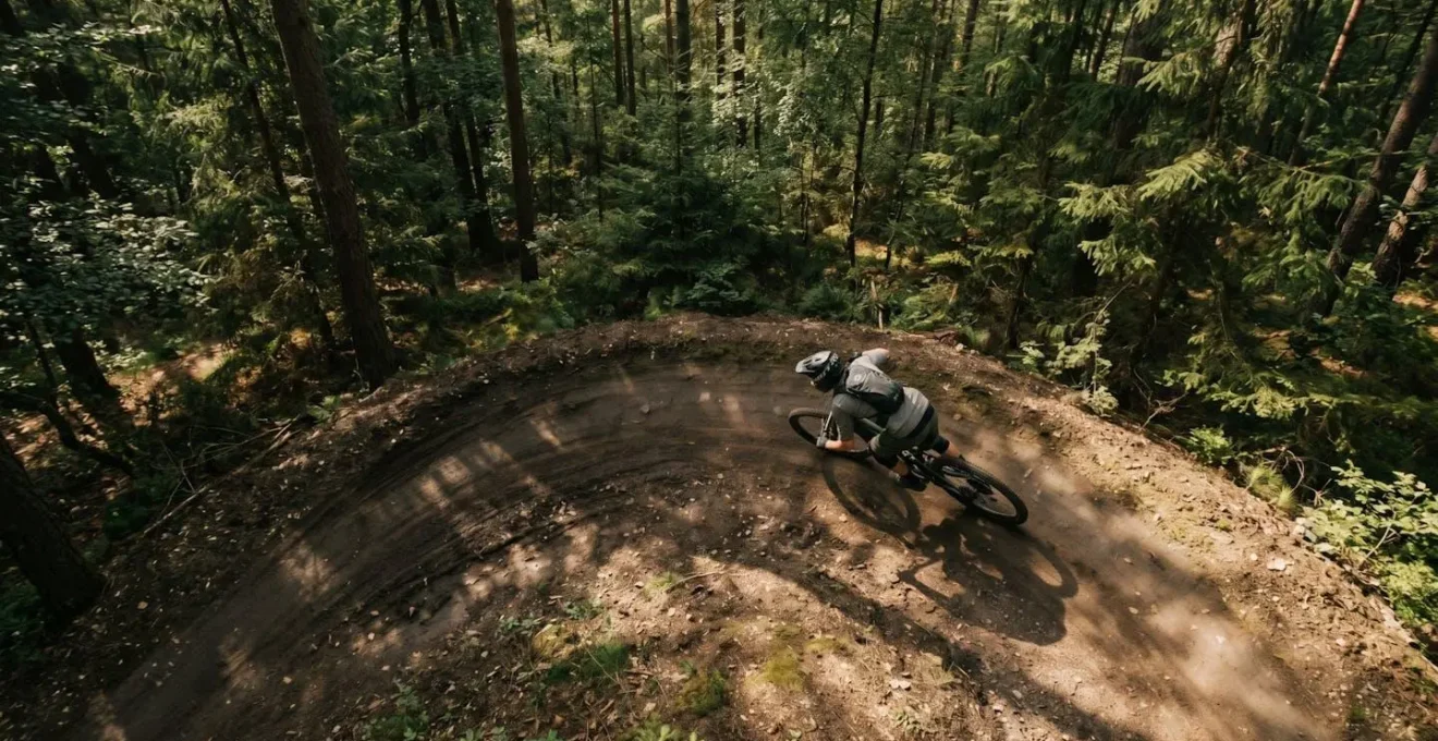 Vue aérienne d'un cycliste VTT négociant un virage relevé en forêt avec la trajectoire idéale